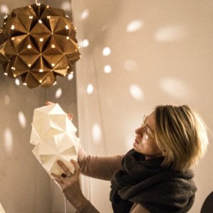 Charlotte Brandt i sit Sonobe Light papirværksted på Vesterbrogade. I baggrunden ses en stor unik foldet lampe i tykt kobberpapir som hun lavede til en udstilling for taastrup Kunstforening